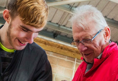 A younger and an elderly person working together happily as part of a National Lottery funded project